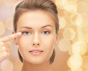 Image showing beautiful young woman pointing finger to her eye