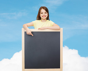 Image showing happy little girl pointing finger to blackboard