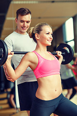 Image showing smiling man and woman with barbell in gym