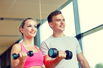 Image showing smiling young woman with personal trainer in gym