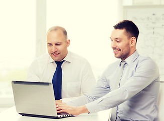 Image showing two smiling businessmen with laptop in office