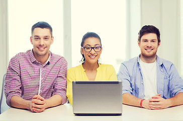 Image showing three smiling colleagues with laptop in office