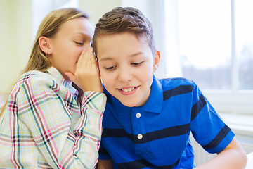 Image showing smiling schoolgirl whispering to classmate ear