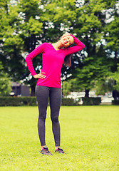 Image showing smiling black woman stretching leg outdoors