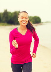 Image showing smiling woman running on track outdoors