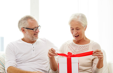 Image showing happy senior couple with gift box at home