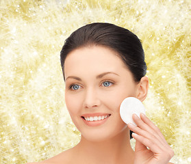 Image showing smiling woman cleaning face skin with cotton pad