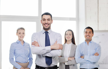 Image showing smiling businessman in office with team on back