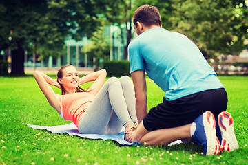 Image showing smiling woman doing exercises on mat outdoors