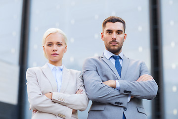 Image showing serious businessmen standing over office building