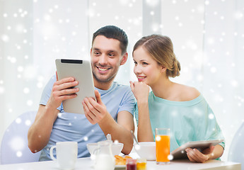 Image showing smiling couple with tablet pc having breakfast