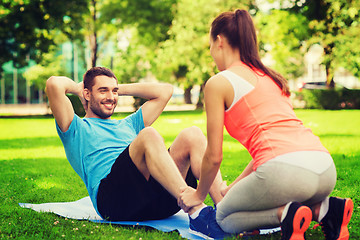 Image showing smiling man doing exercises on mat outdoors