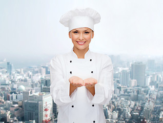 Image showing smiling female chef holding something on hands