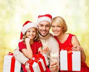 Image showing smiling family holding gift boxes and sparkles