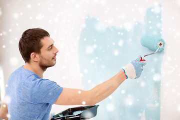 Image showing smiling young man with roll and tray painting wall