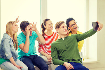 Image showing smiling students making picture with tablet pc