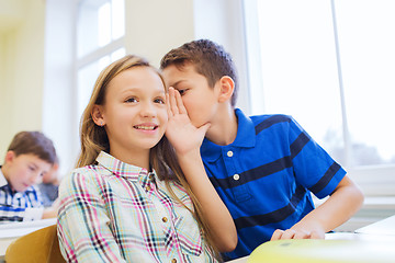 Image showing smiling schoolboy whispering to classmate ear