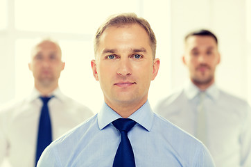 Image showing serious businessman in office with team on back