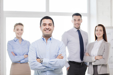 Image showing smiling businessman in office with team on back