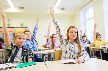 Image showing group of school kids raising hands in classroom