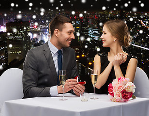 Image showing smiling couple with red gift box at restaurant