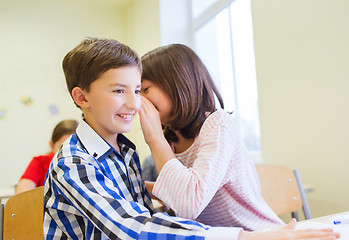 Image showing smiling schoolgirl whispering to classmate ear