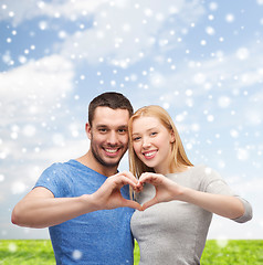 Image showing happy couple making heart gesture and hugging