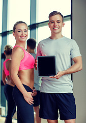 Image showing smiling young woman with personal trainer in gym