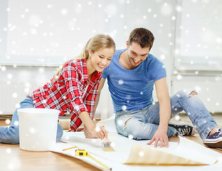 Image showing smiling couple smearing wallpaper with glue