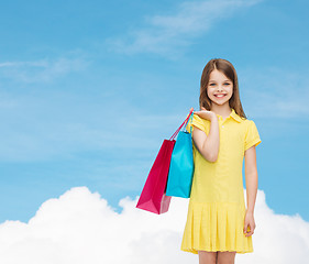 Image showing smiling little girl in dress with shopping bags