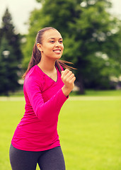 Image showing smiling young woman running outdoors