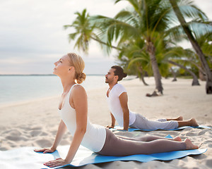 Image showing happy couple making yoga exercises on beach