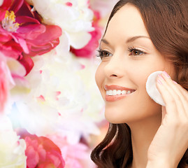 Image showing smiling woman cleaning face skin with cotton pad