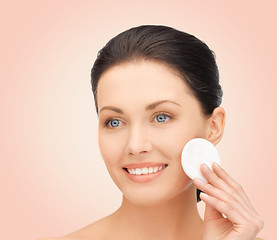 Image showing smiling woman cleaning face skin with cotton pad