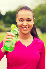 Image showing smiling woman drinking from bottle