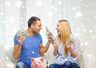 Image showing happy couple with money and piggybank at home