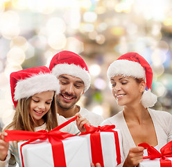 Image showing happy family in santa helper hats with gift boxes