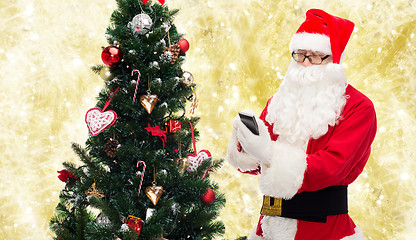 Image showing santa claus with smartphone and christmas tree