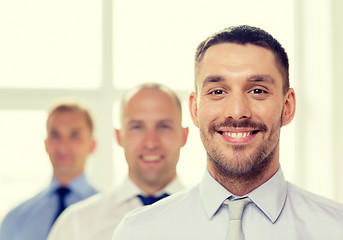 Image showing smiling businessman in office with team on back