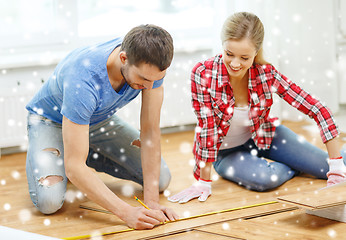 Image showing smiling couple measuring wood flooring