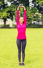 Image showing smiling black woman stretching leg outdoors