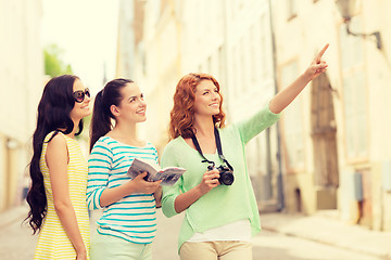 Image showing smiling teenage girls with city guide and camera