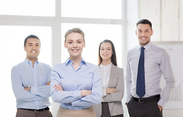 Image showing smiling businesswoman in office with team on back