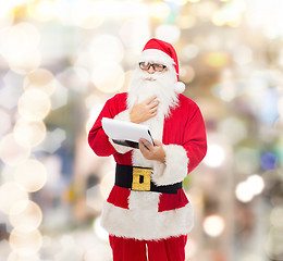 Image showing man in costume of santa claus with notepad