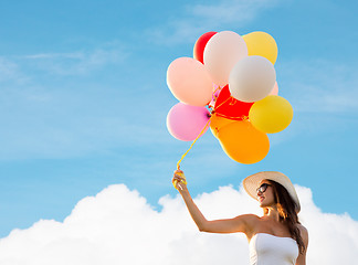 Image showing smiling young woman in sunglasses with balloons