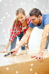 Image showing smiling couple opening big cardboard box