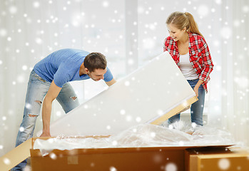 Image showing smiling couple opening big cardboard box with sofa