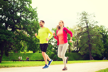 Image showing smiling couple with earphones running outdoors