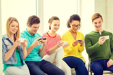 Image showing smiling students with smartphone texting at school