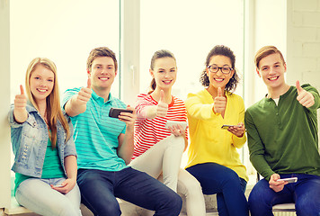 Image showing smiling students with smartphone texting at school